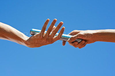 Buy stock photo Cropped shot of two athletes passing the baton during a relay race