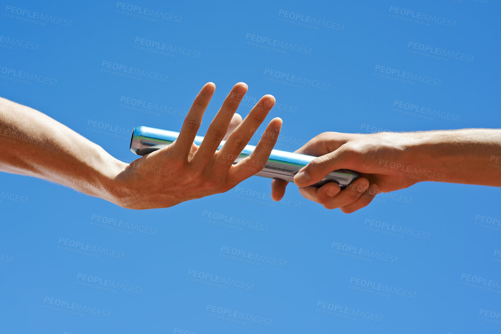 Buy stock photo Cropped shot of two athletes passing the baton during a relay race