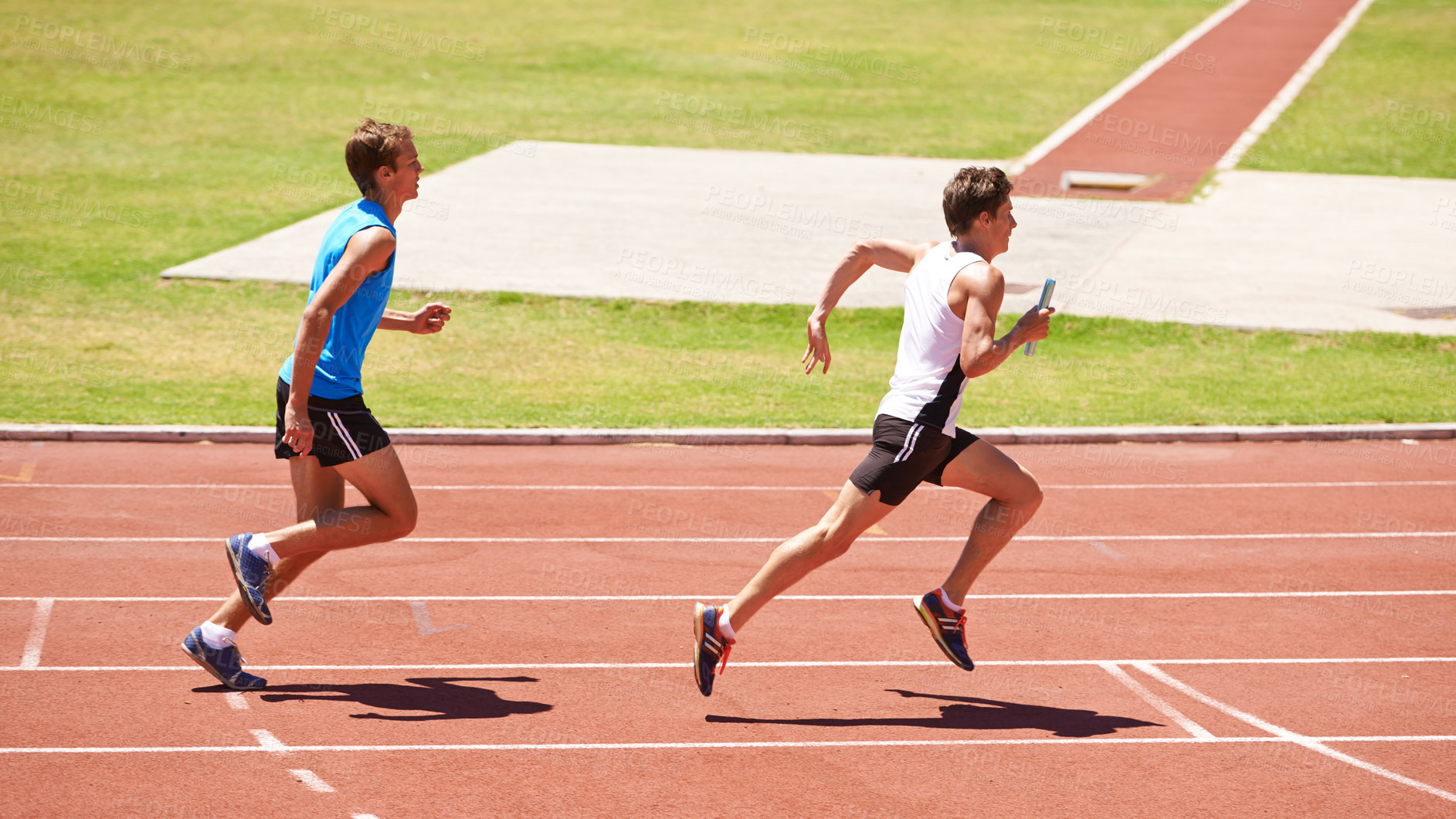 Buy stock photo Shot of two young athletes running in a relay race