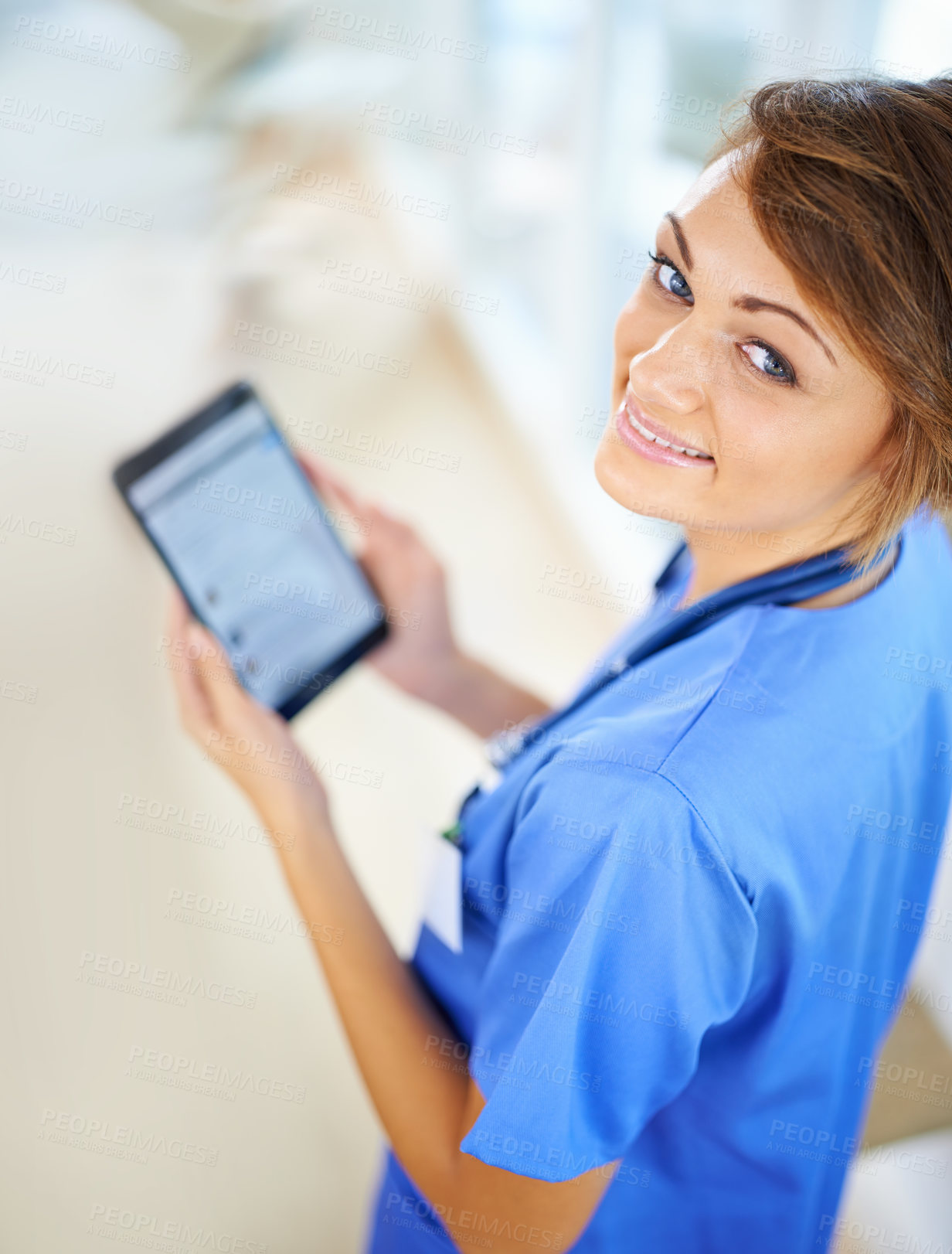 Buy stock photo Portrait of an attractive young doctor in scrubs holding a digital tablet