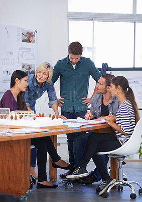 Buy stock photo Cropped shot of a group of architects discussing a scale model