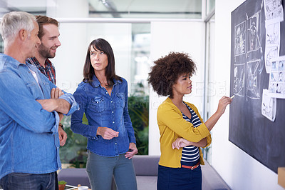 Buy stock photo Shot of a team of coworkers planning a storyboard on a blackboard