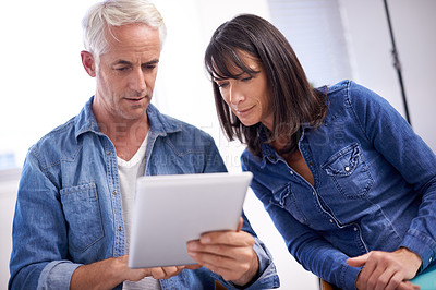 Buy stock photo Shot of two coworkers looking at a digital tablet