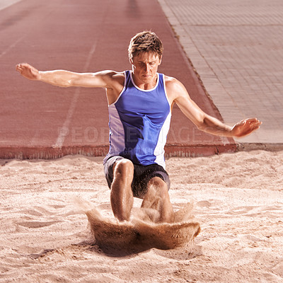 Buy stock photo Fitness, sand and long jump with athlete man on track in stadium for competition or performance. Exercise, event and sports with confident young person at arena or venue for challenge and effort