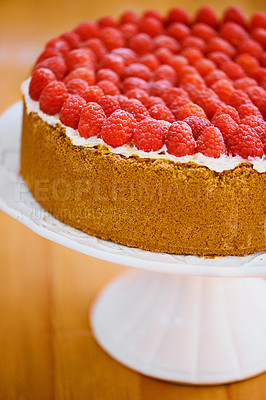 Buy stock photo Stand, frosting and cheesecake with raspberries on table for sweet snack for tea time at home. Bakery, catering and closeup of gourmet dessert with crust, cream and fresh organic fruit in dining room