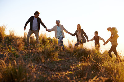 Buy stock photo Shot of a happy family holding hands on a morning walk together