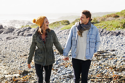 Buy stock photo Holding hands, love and couple by ocean walking for bonding, romantic relationship and relax outdoors. Nature, travel and happy man and woman by sea for winter holiday, vacation and weekend together