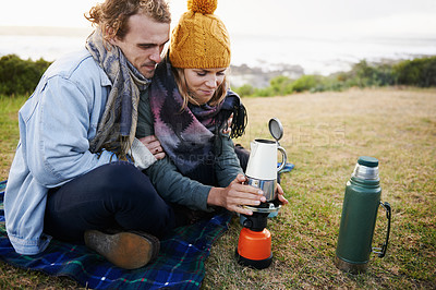 Buy stock photo Happy couple, coffee and camping together in nature, travel and romantic getaway with bonding by beach. Man, woman or love on vacation with espresso on gas, countryside or relax on grass for drink