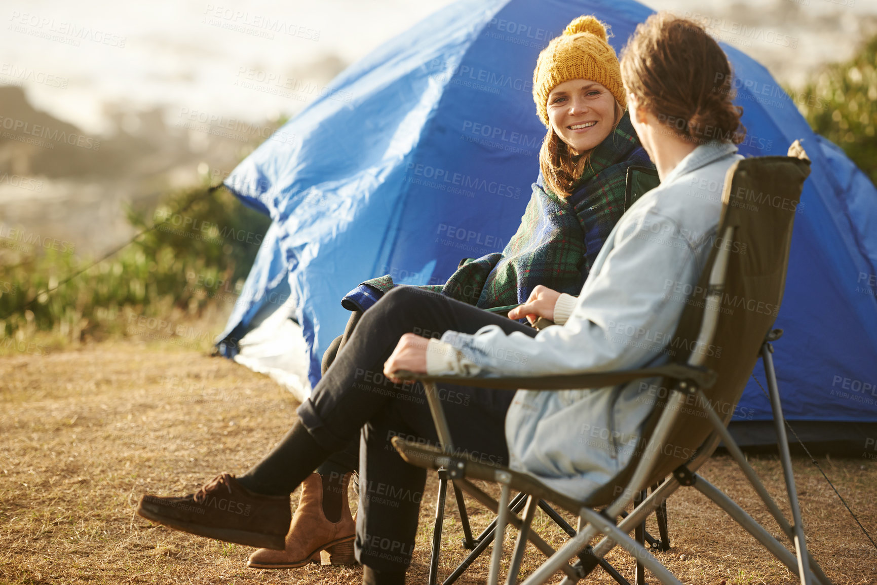 Buy stock photo Conversation, camping and couple by tent on vacation, adventure or holiday in woods. Smile, love and young man and woman talking, bonding and relaxing in outdoor forest for weekend trip in nature.