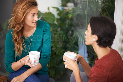 Buy stock photo Shot of two female professionals having a discussion over coffee in an informal office setting
