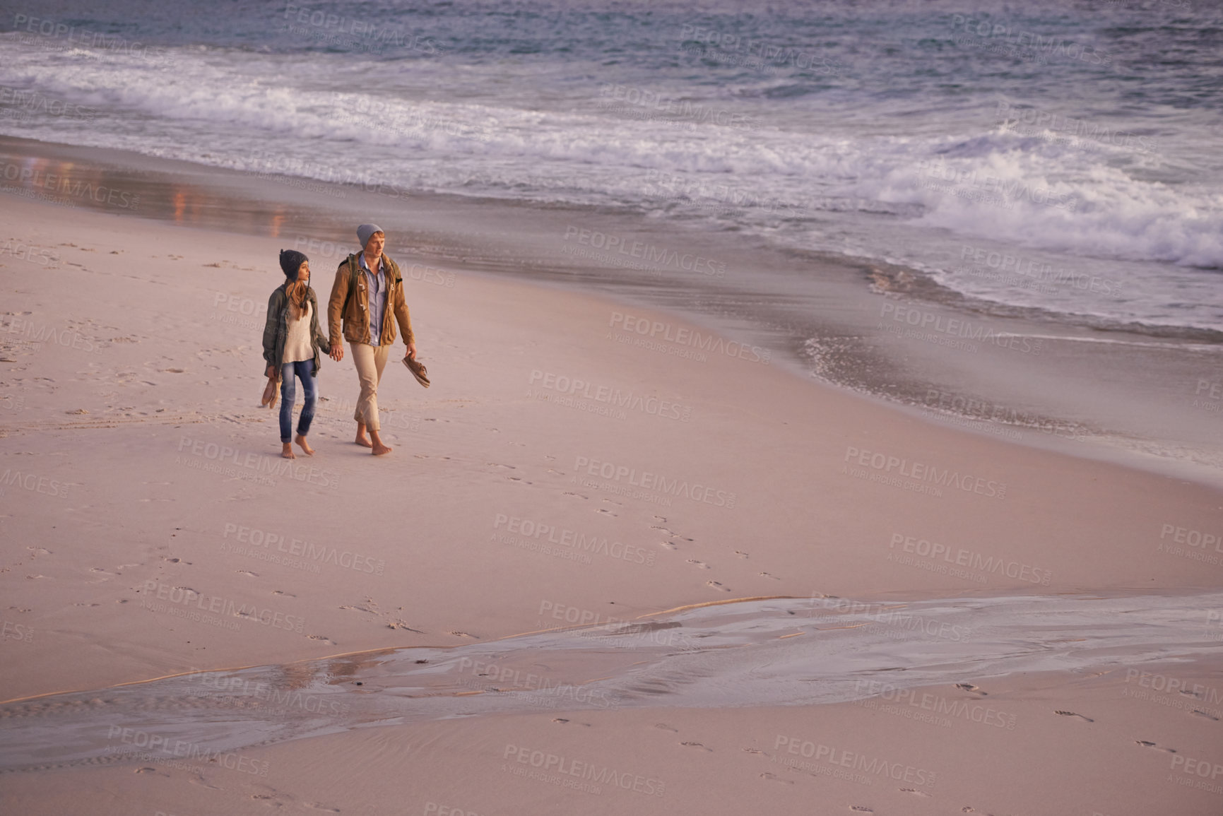 Buy stock photo Couple, holding hands and love for walking on shore, ocean waves and peace for romance in relationship. People, beach and security in marriage, sea and travel together on vacation or holiday for date
