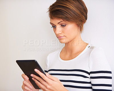 Buy stock photo Woman, reading and tablet on a white background for online information, streaming and search by a wall or at home. Young and casual person with digital technology for ebook, internet and social media