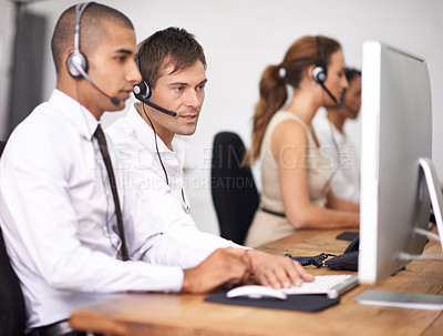 Buy stock photo Shot of a group of help desk operators wearing headsets and working in an office