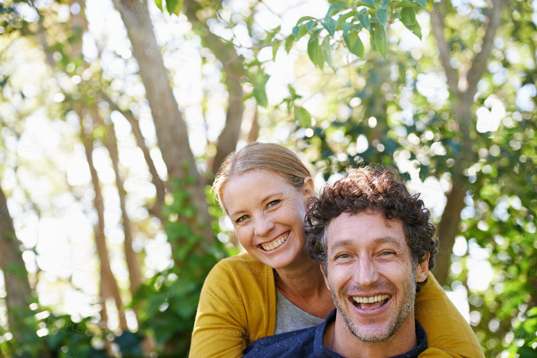 Buy stock photo Happy, couple and piggyback outdoor in portrait for love and bonding, trust and support in commitment for marriage. Partner, loyalty and fun with people in nature for fresh air on date for romance