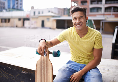 Buy stock photo Portrait of a young man sitting with his skateboard in the city