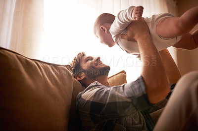 Buy stock photo Smile, father and lifting baby on sofa in home living room, playing or bonding together. Funny, care and dad holding infant, newborn or child on couch in lounge, having fun and enjoying quality time.