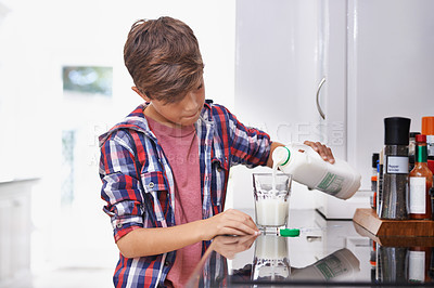 Buy stock photo A young boy pouring himself a glass of milk in the kitchen