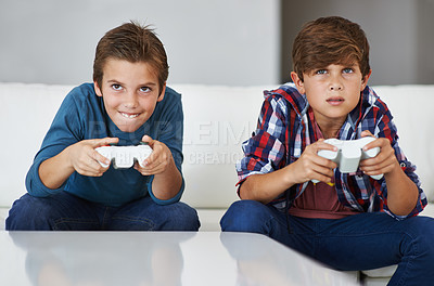 Buy stock photo Shot of two young boys concentrating while playing video games