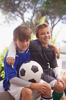 Buy stock photo Shot of two young boys sitting outside with a soccer ball
