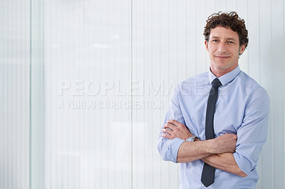 Buy stock photo Cropped shot of a young businessman standing in an office with his arms crossed