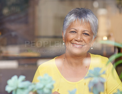 Buy stock photo Shot of a mature woman sitting behind a glass window of a coffee shop