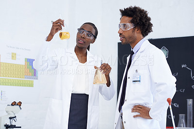 Buy stock photo Shot of two scientists conducting an experiment in their lab