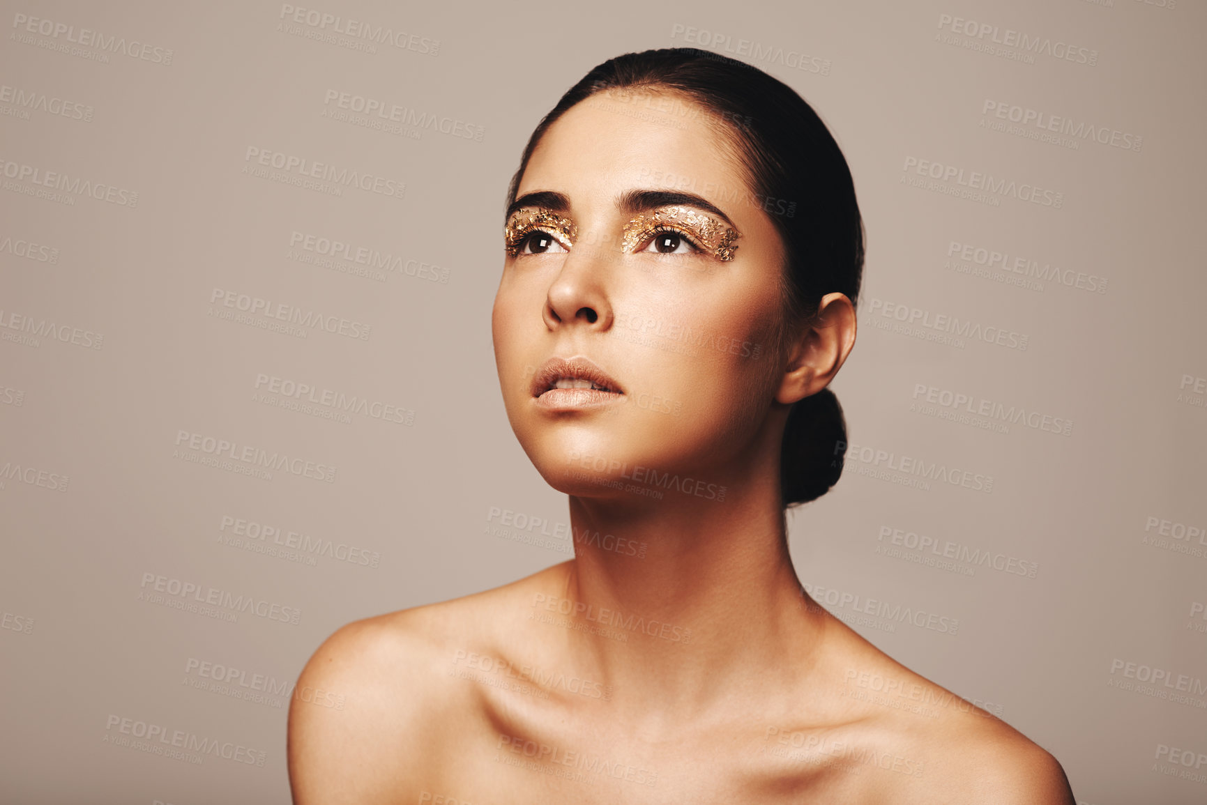 Buy stock photo Studio shot of a gorgeous brunette looking up with gold painted eyes