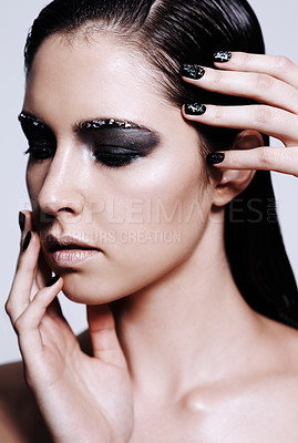 Buy stock photo Studio shot of a beautiful young woman wearing metallic-colored makeup and nail polish