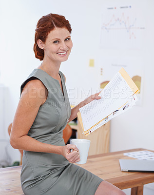 Buy stock photo Portrait of an attractive young businesswoman having coffee while looking at paperwork