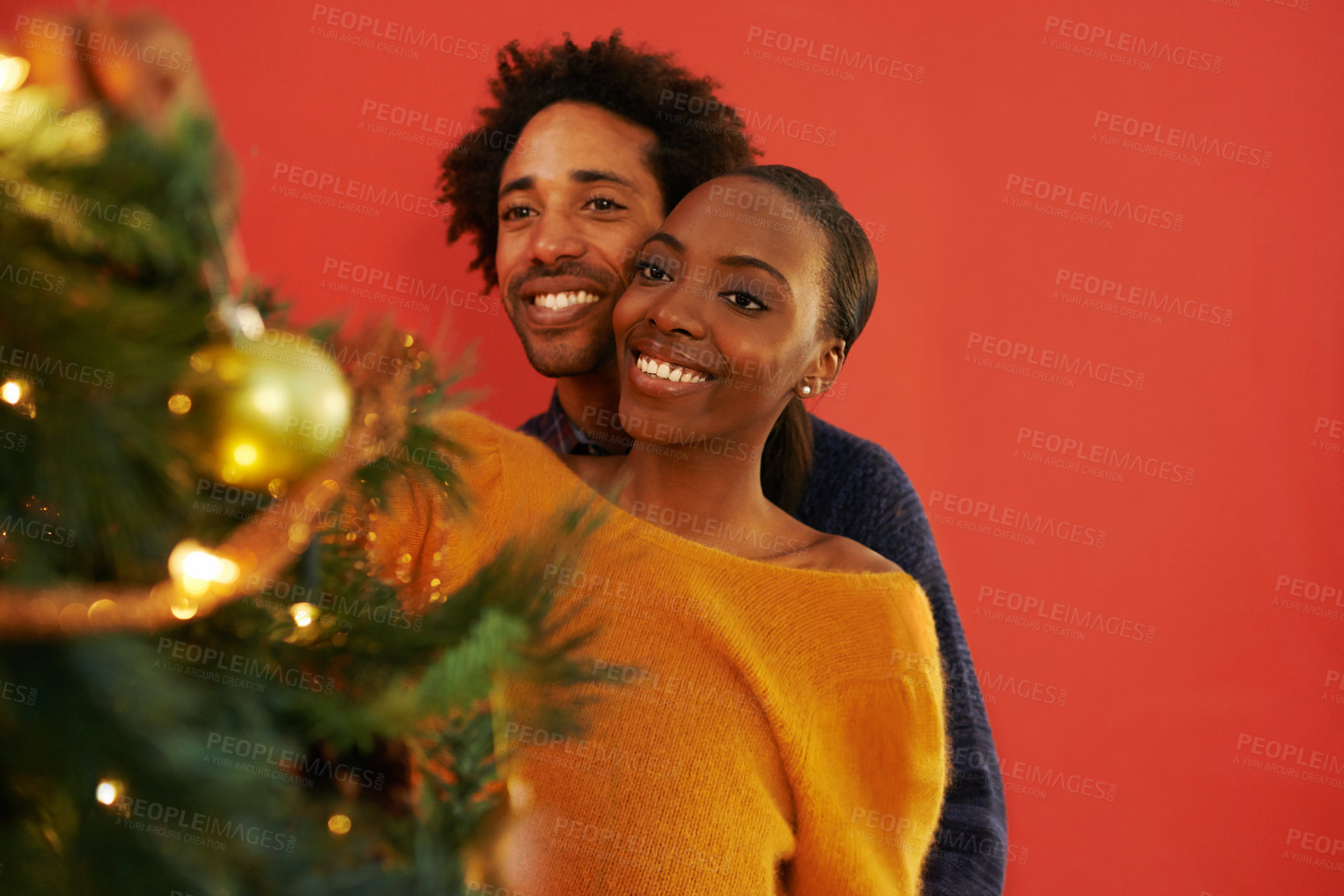 Buy stock photo Shot of a loving young couple decorating their Christmas tree