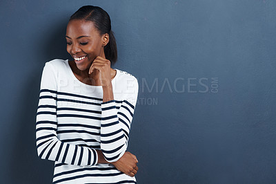 Buy stock photo Shot of an attractive young woman smiling shyly on a gray background