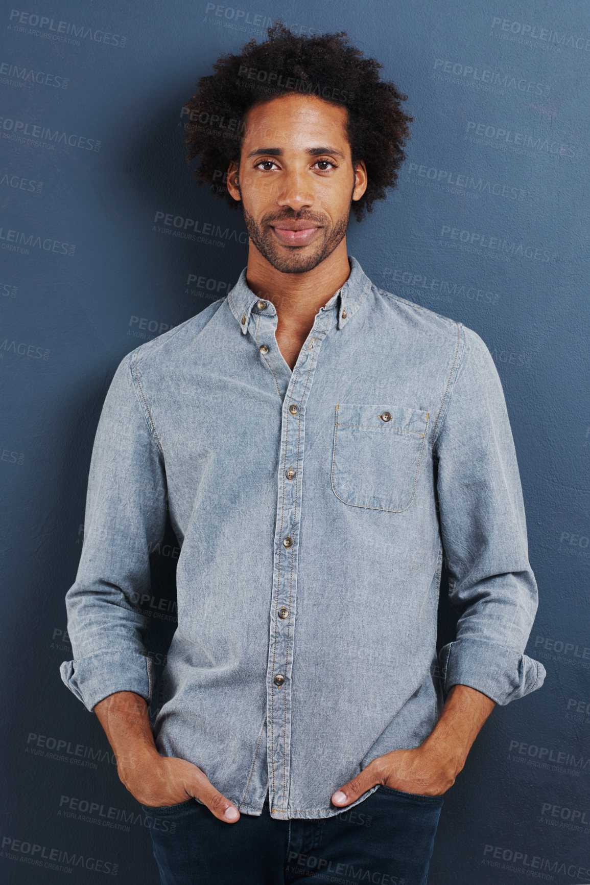 Buy stock photo Black man, portrait and casual for fashion with denim shirt, calm and cool in studio with afro on blue background. African model with smile, pride and pose with hands in pocket and stylish clothes