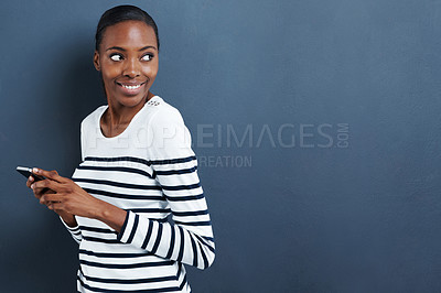 Buy stock photo Shot of an attractive young woman using her phone on a gray background