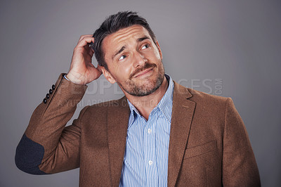 Buy stock photo Studio shot of a man scratching his head against a gray background