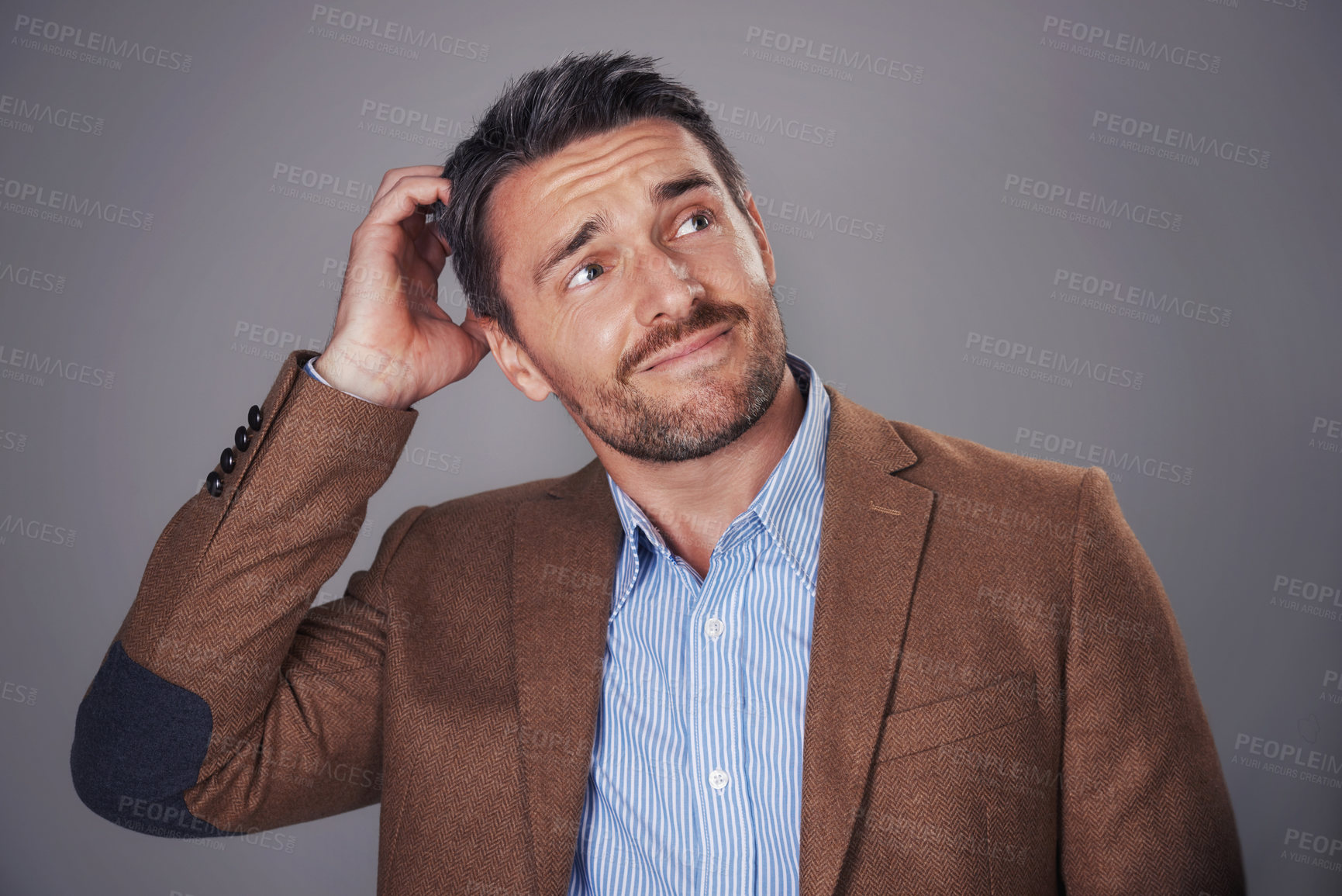 Buy stock photo Studio shot of a man scratching his head against a gray background