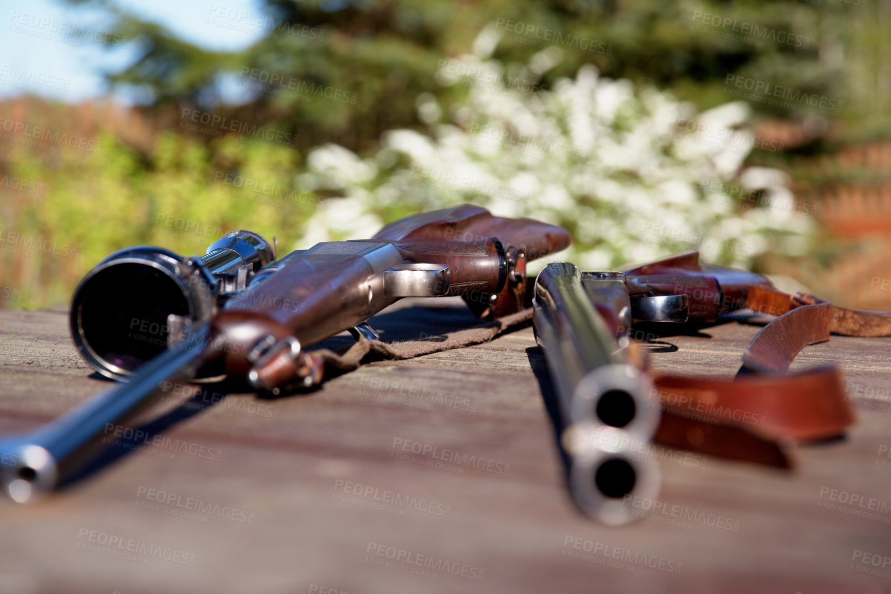 Buy stock photo Shot of two guns lying on a table outside