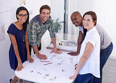 Buy stock photo Shot of young team of architects standing around a table in an office