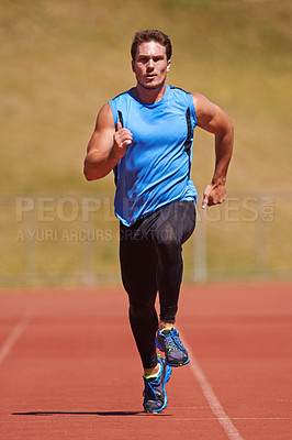 Buy stock photo Action shot of a young male athlete running on a track