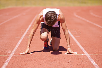 Buy stock photo Shot of a young male athlete at the start of a track race