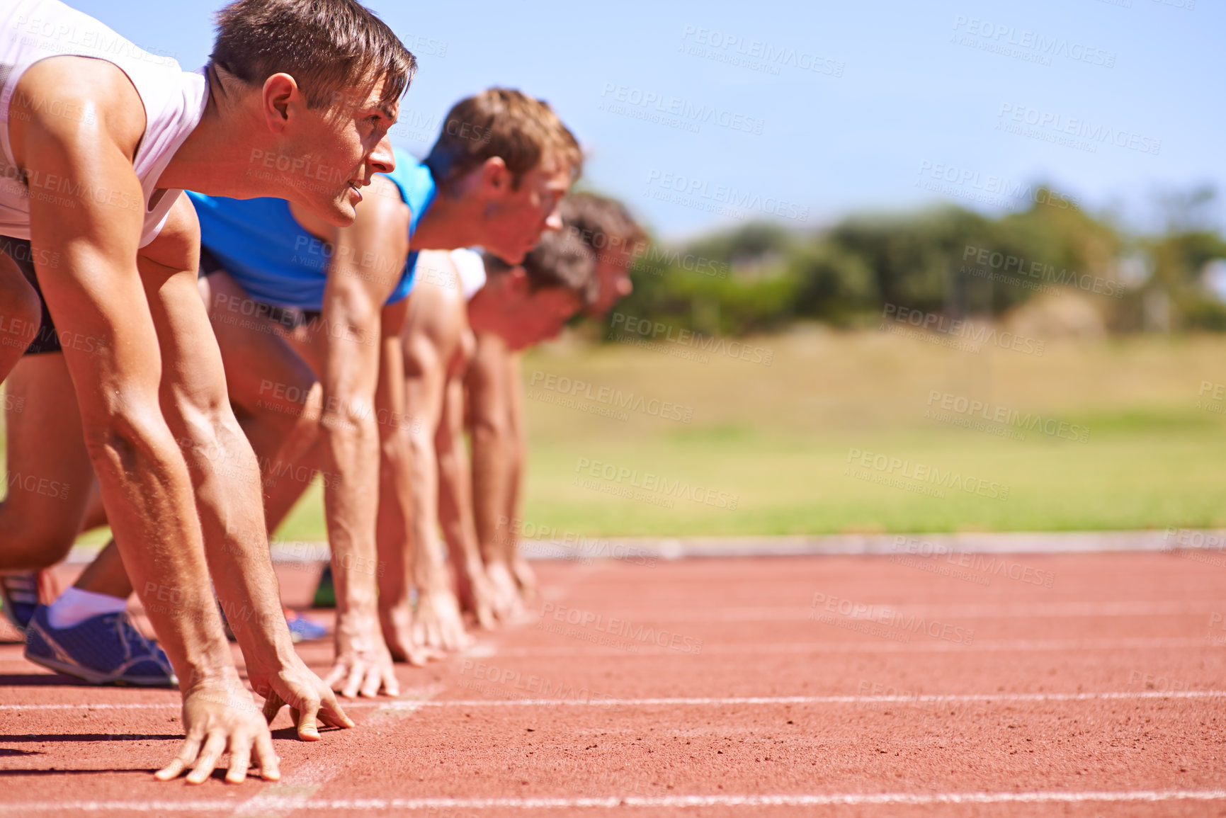 Buy stock photo Cropped side view of a group of athletes at the start of a track race