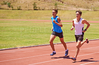 Buy stock photo Shot of two male athletes running on a track