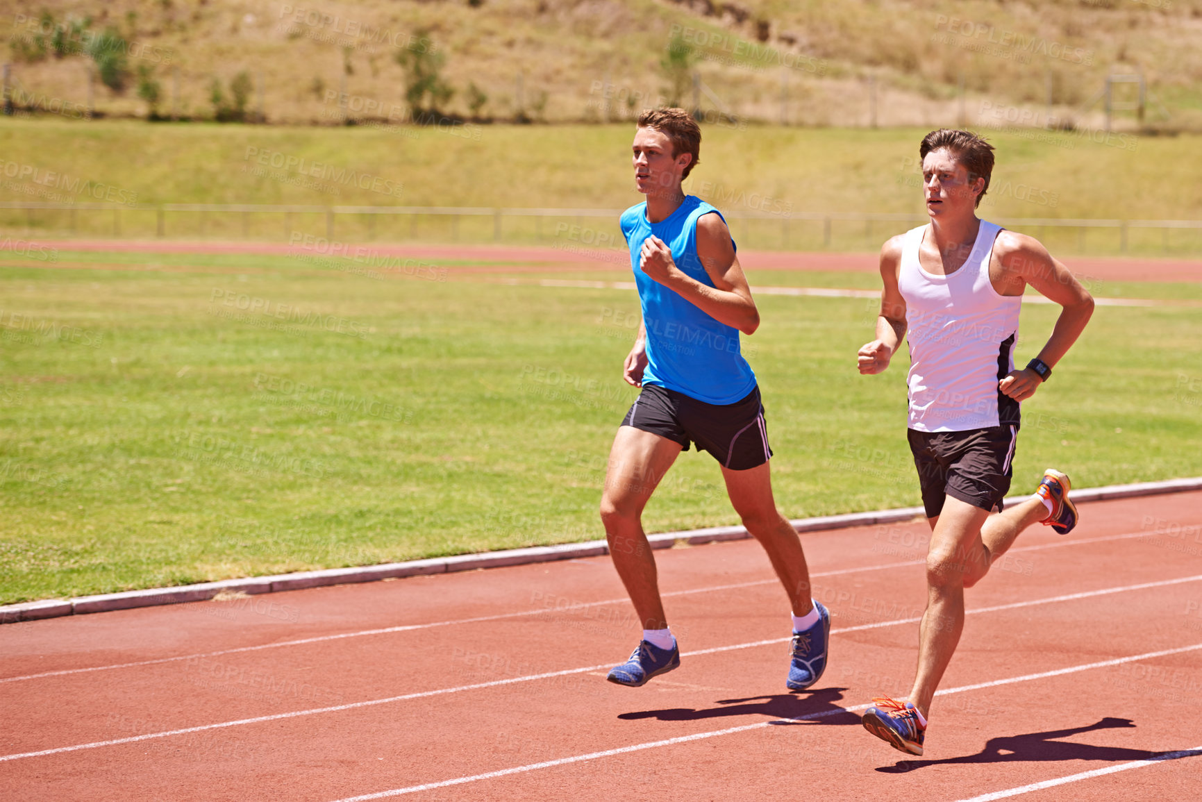 Buy stock photo Shot of two male athletes running on a track