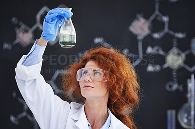 Buy stock photo A cropped shot of a young frizzy-haired scientist examining a flask in her lab