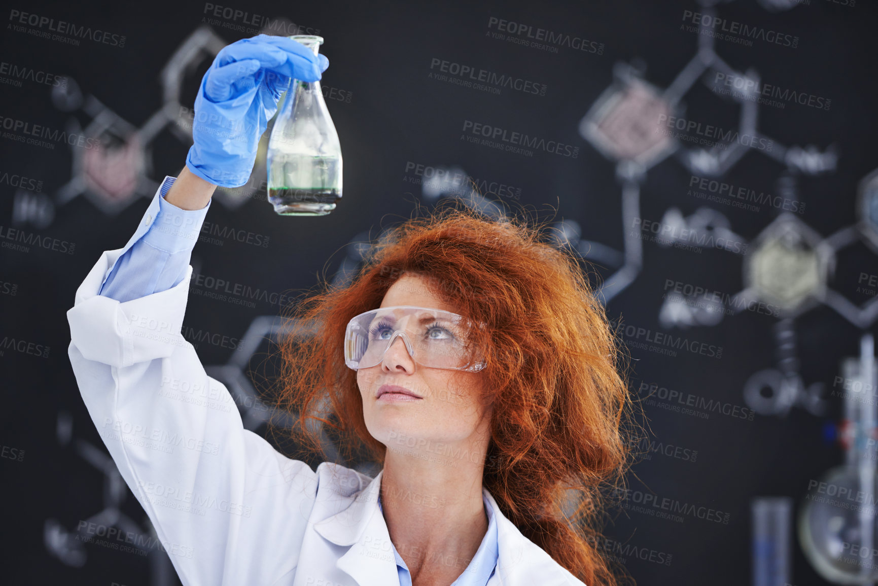 Buy stock photo A cropped shot of a young frizzy-haired scientist examining a flask in her lab