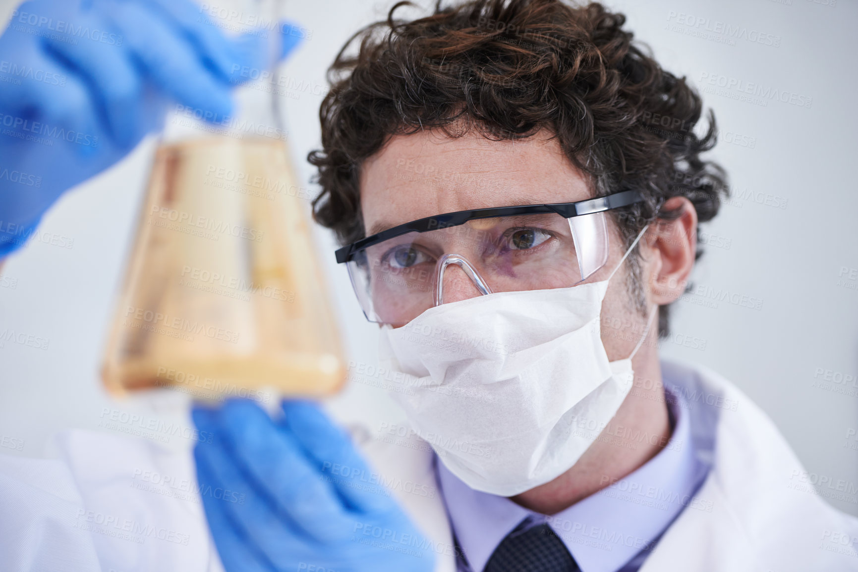 Buy stock photo A cropped shot of a scientist examining a flask filled with liquid