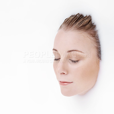 Buy stock photo Studio shot of an attractive woman's face emerging from a white liquid