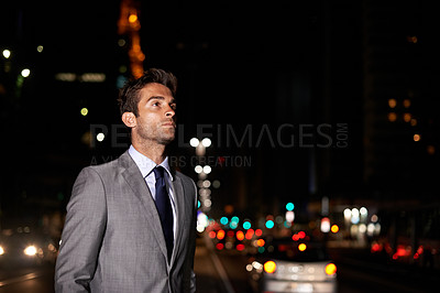 Buy stock photo A handsome businessman standing in the middle of a busy city street at night