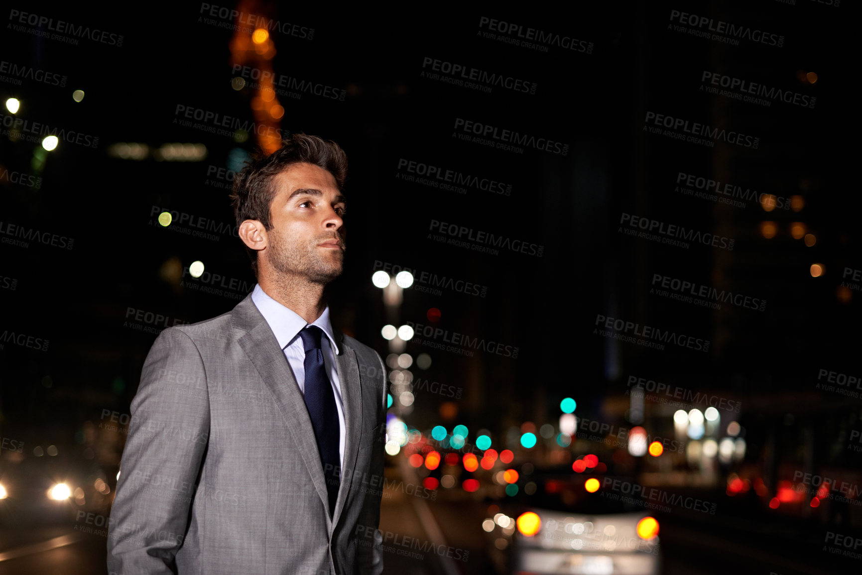 Buy stock photo A handsome businessman standing in the middle of a busy city street at night