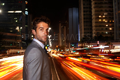 Buy stock photo A portrait of a handsome businessman standing in the middle of a busy city street at night
