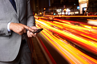 Buy stock photo A cropped shot of a businessman texting while standing beside a busy road